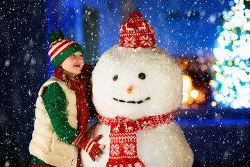 Kids and snowman in garden at Christmas fireplace.