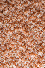 Image of cane sugar. The sugar is in a scattered state. Granules are clearly visible. The color of sugar is brown.