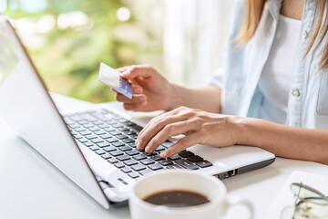 Young woman holding a credit card and using computer for making online payment shopping