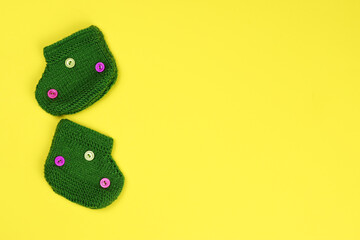 Baby socks knitted isolated on yellow background. Space for text