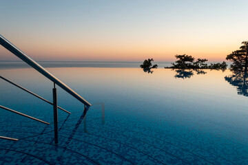 Entry of endless swimming pool with calm water and nobody in it during magnificent sunset  