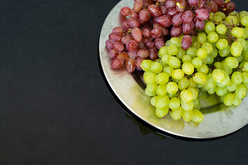 Bunch of red and green organic grapes on the silver plate with copy space for your text 