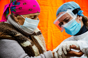 Tired female doctor in a mask in the red zone in the fight against coronavirus infection.Hard days of doctors in the fight against coronavirus infection.Doctor in a protective suit examines a patient 
