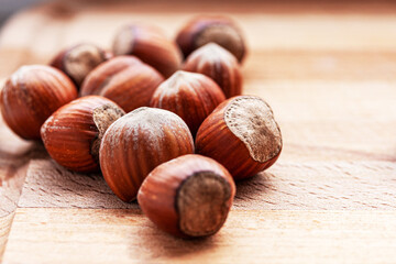 Close-up of several hazelnuts on a light wooden surface. Selective focus.