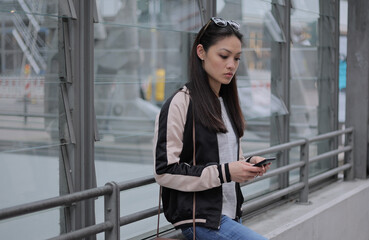 Young Asian woman writes text messages on her phone