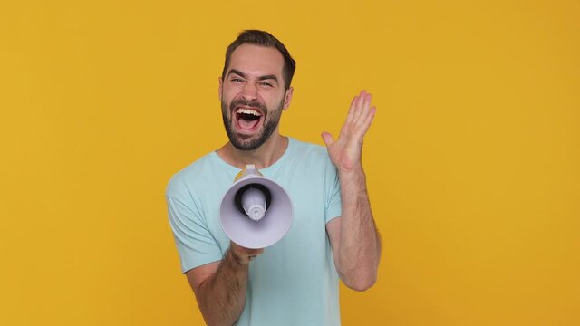 Funny excited young man 20s years old in basic casual blue t-shirt isolated on yellow background studio. People lifestyle concept. Looking camera scream in megaphone announces discounts sale Hurry up