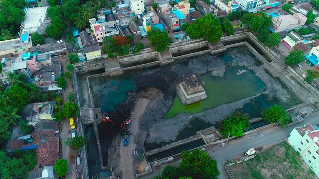 Aerial view of a pond being cleaned in front of the temple