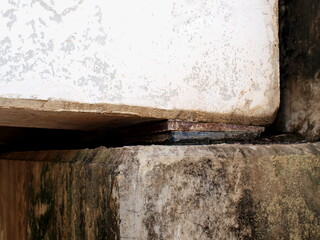 Old elastomeric Bearing Pad. Black rubber bridge support with metal pads under dirty and rusty concrete bars. Because it has been in use for a long time Close focus and choose a subject