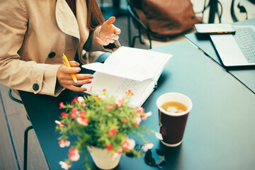 Photo of a woman planning her day sitting at a table at a cafe with a coffee .
