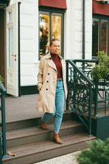 A woman walking downstairs outside is smiling at the camera .