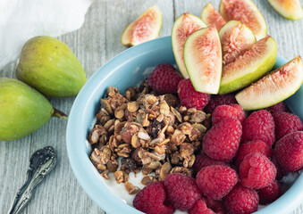 Bowl of Greek yogurt with rasberries, figs and granola.