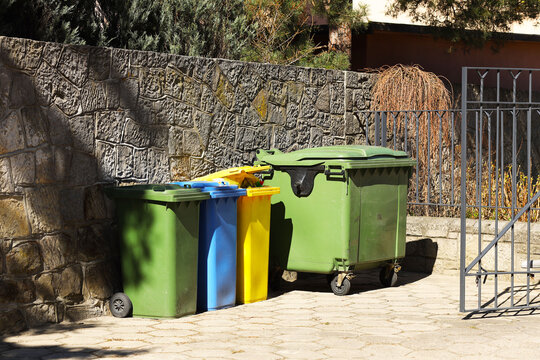 Four multicolored boxes for sorted garbage: green, blue and yellow. Recycling garbage in the tourist area. Infrastructure of the Mediterranean marina. Plastic waste containers