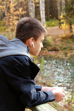 Thoughtful teenage boy listening to music with headphones outdoor