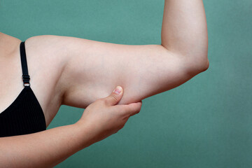 Conscious young woman holding excess fat on her arm against