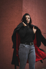 Naklejka premium A girl in a black cloak on a red background.