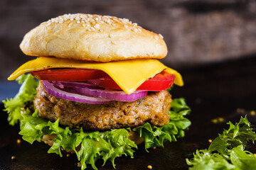 Fresh delicious homemade veggie burger lies on natural slate on rustic wooden background. Delicious tasty burger with lettuce, cheese, onion and tomato. buckwheat and lentil cutlet