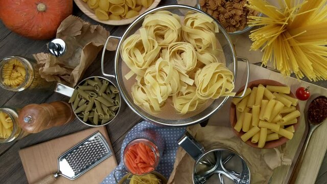 Various types of raw pasta rotate slowly. Macro background. View from top