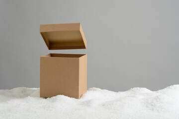 Caja de regalos en la nieve con la tapa elevada sobre la caja