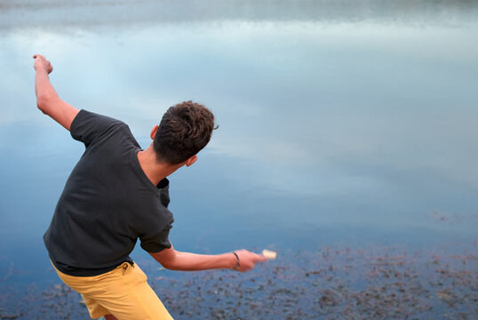 Caucasian man throwing stones into the lake