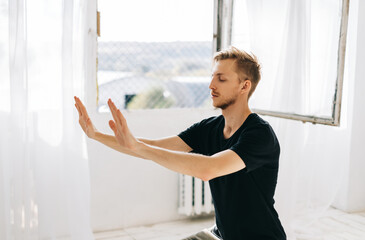 Young caucasian man meditate, doing yoga indoors at home. Staying fit and healthy