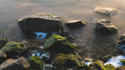 Long exposure close up view of rocks in the sea at sunset