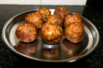  Indian Vegetarian koftas made with bottle gourd and gram flour as a main ingredients with onion, coriander leaf kept aside after deep frying.
- 387813360