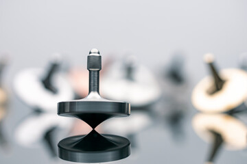 Beautiful metallic heavy spinning top spinning on glass surface with many spinning in blur...