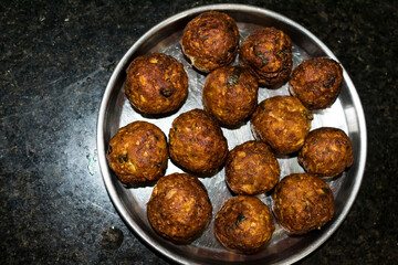  Indian Vegetarian koftas made with bottle gourd and gram flour as a main ingredients with onion, coriander leaf kept aside after deep frying.
- 387813747