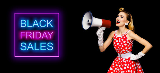 Beauty blond pinup woman holding megaphone, shout something. Girl in pin up style dress in polka dot, over dark background. Retro fashion vintage concept photo. Black Friday neon light sign.