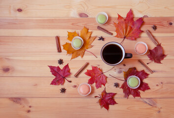 Mug of coffee, autumn leaves, macaroon cookies  and spices on wooden table. Top view, copy space.