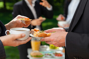 Two businesspeople with coffee and sandwiches during outdoor business lunch
