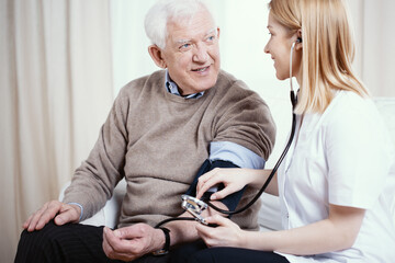 Senior grey man with supporting measuring blood pressure