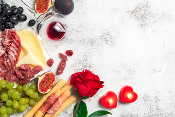 Valentines Day background with appetizers on table italian antipasto snacks and wine. Grape, figs, cheese, bread, prosciutto, meat snaks. Antipasti, gourmet, romantic concept. Copy space