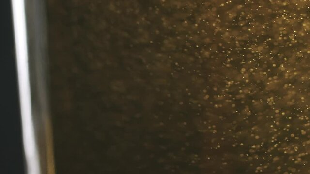 Macro shot of beer in a glass. Shaking the glass a little bit. A lot of small bubbles visible.