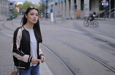 Young Asian woman waits for the tram in the city - urban photography