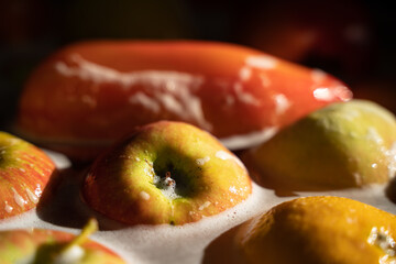 Ripe vegetables and fruits in soapy water. Red apple in the center