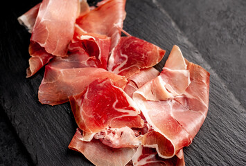 Spanish jamon Serrano, against a stone background	