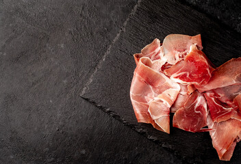 Spanish jamon Serrano, against a stone background with copy space