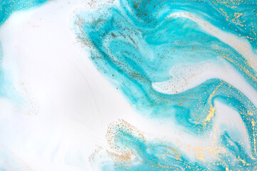 Gold and light blue mixed inks spilled background. Turquoise texture.