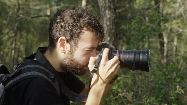 Male Caucasian Photographer takes photos in a dense green forest during the day