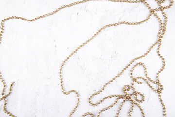 Christmas garland on white concrete background. Golden christmas decorations on stone cement surface.
