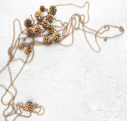 Christmas garland and golden cones on white concrete background., top view Golden christmas decorations on stone cement surface with copy space.