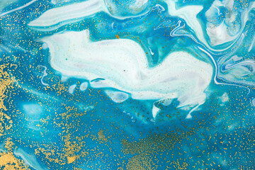 Fototapeta na wymiar Gold and light blue mixed inks spilled background. Turquoise texture.