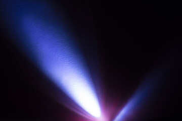Cool blue light from an LED flashlight on a white wall. A ray of light on the surface.