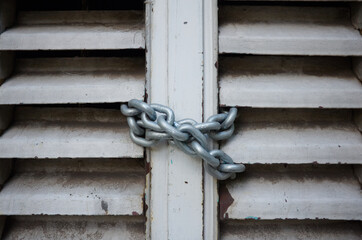 Metal chain hanging on closed entrance to the building close up.