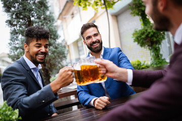 Handsome businessmen are drinking beer, talking and smiling while resting at the pub