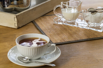 Cup of tea with teapot, sugar and milk on a wooden table. Tea time in east frisia.