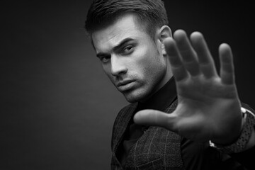 Black and white portrait of beautyful guy on dark background. High fashion model posing in studio....
