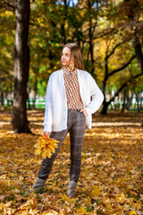 Blonde teenage girl posing in autumn park