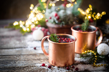 Mulled wine with cranberry in copper mug with christmas decorations on wooden table